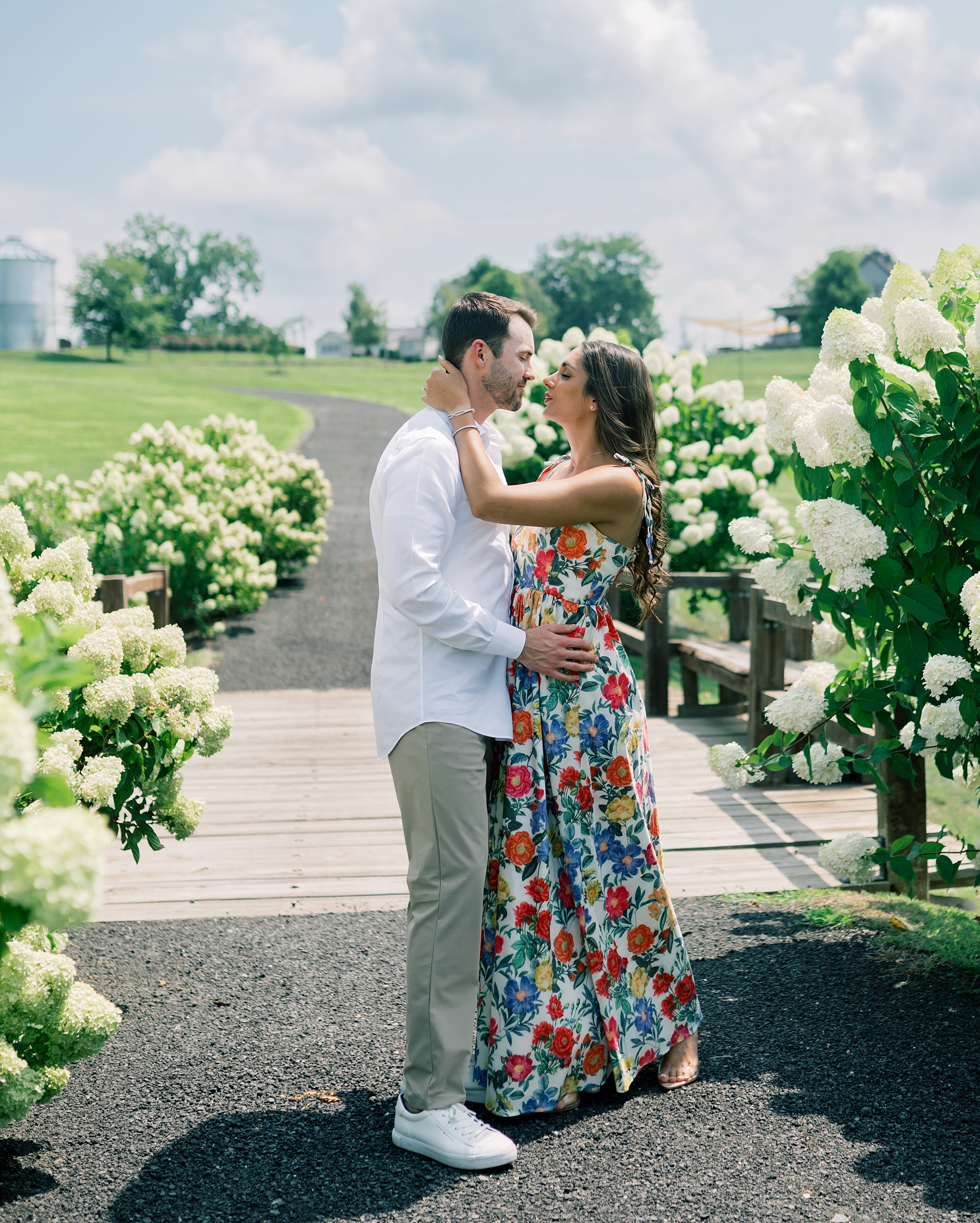 man and woman kiss hugging between white hydrangeas 