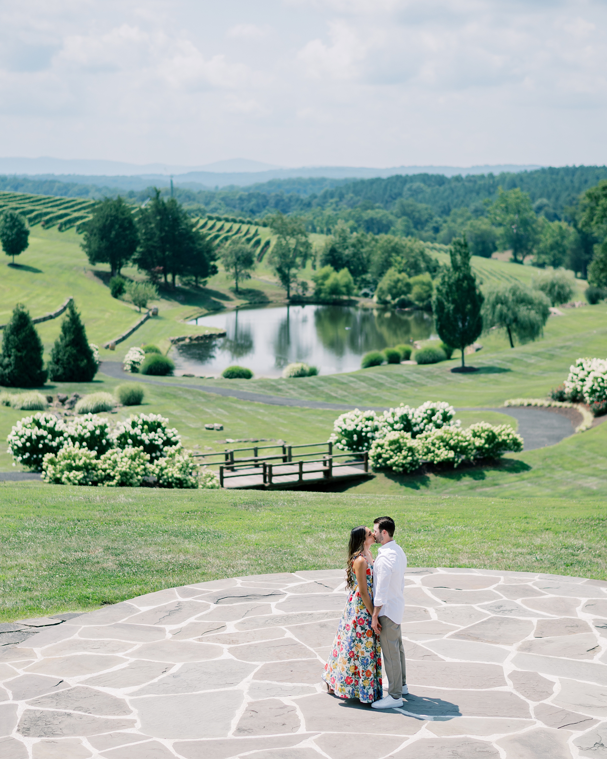 engaged couple stand on stone patio looking out over Stone Tower Winery