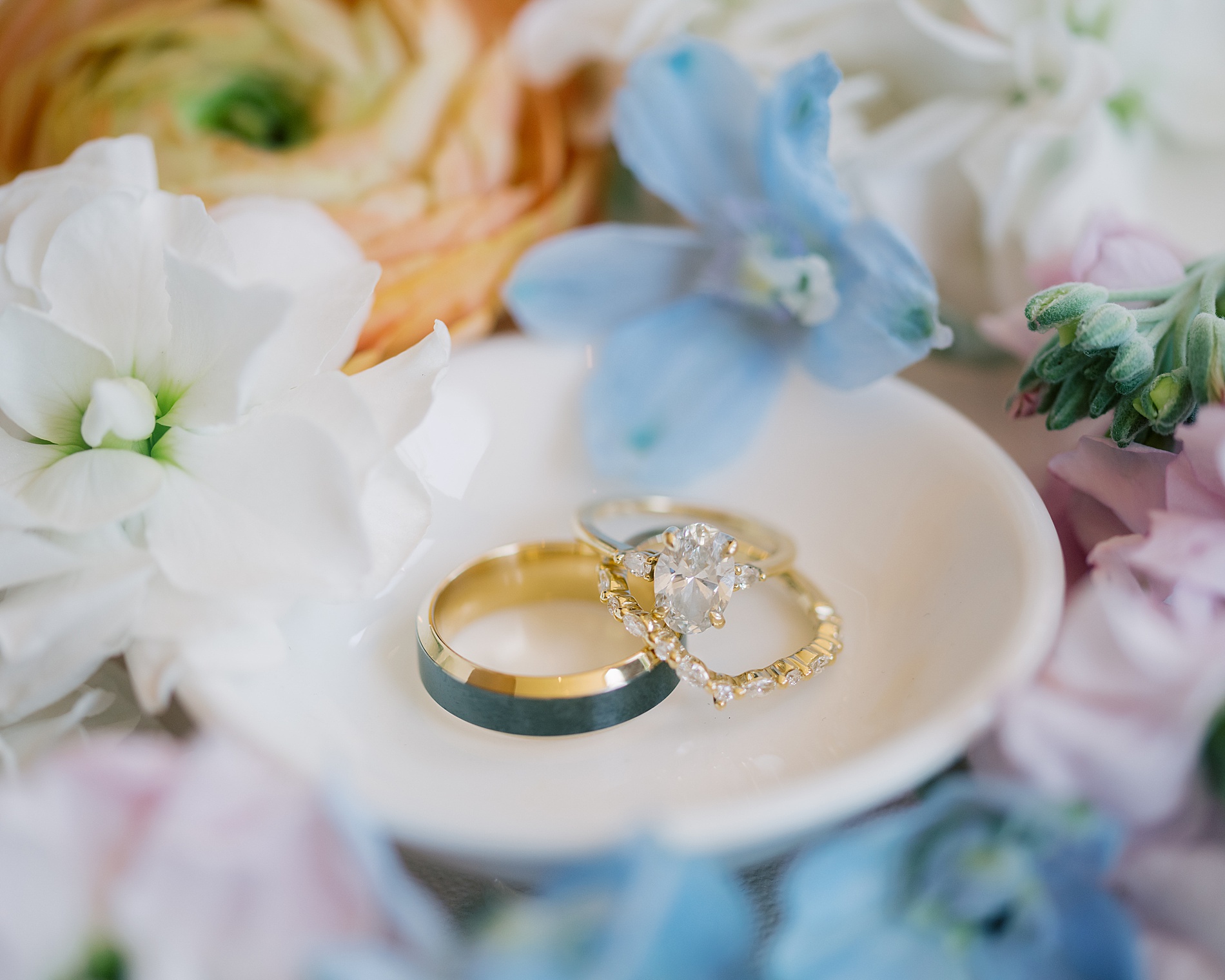 wedding jewelry on small styling dish surrounded by flowers
