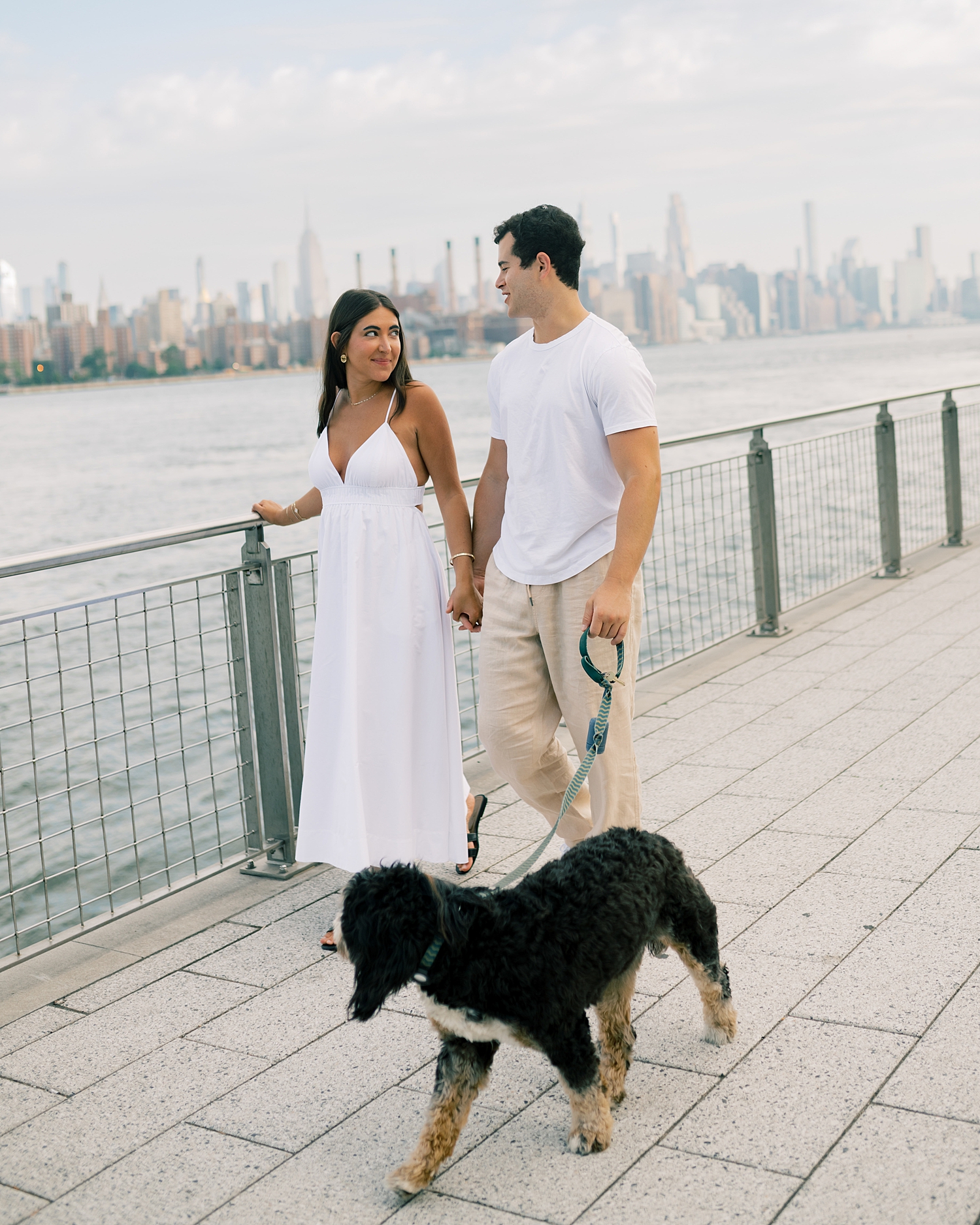 couple walk by the water in Baltimore with their dog 