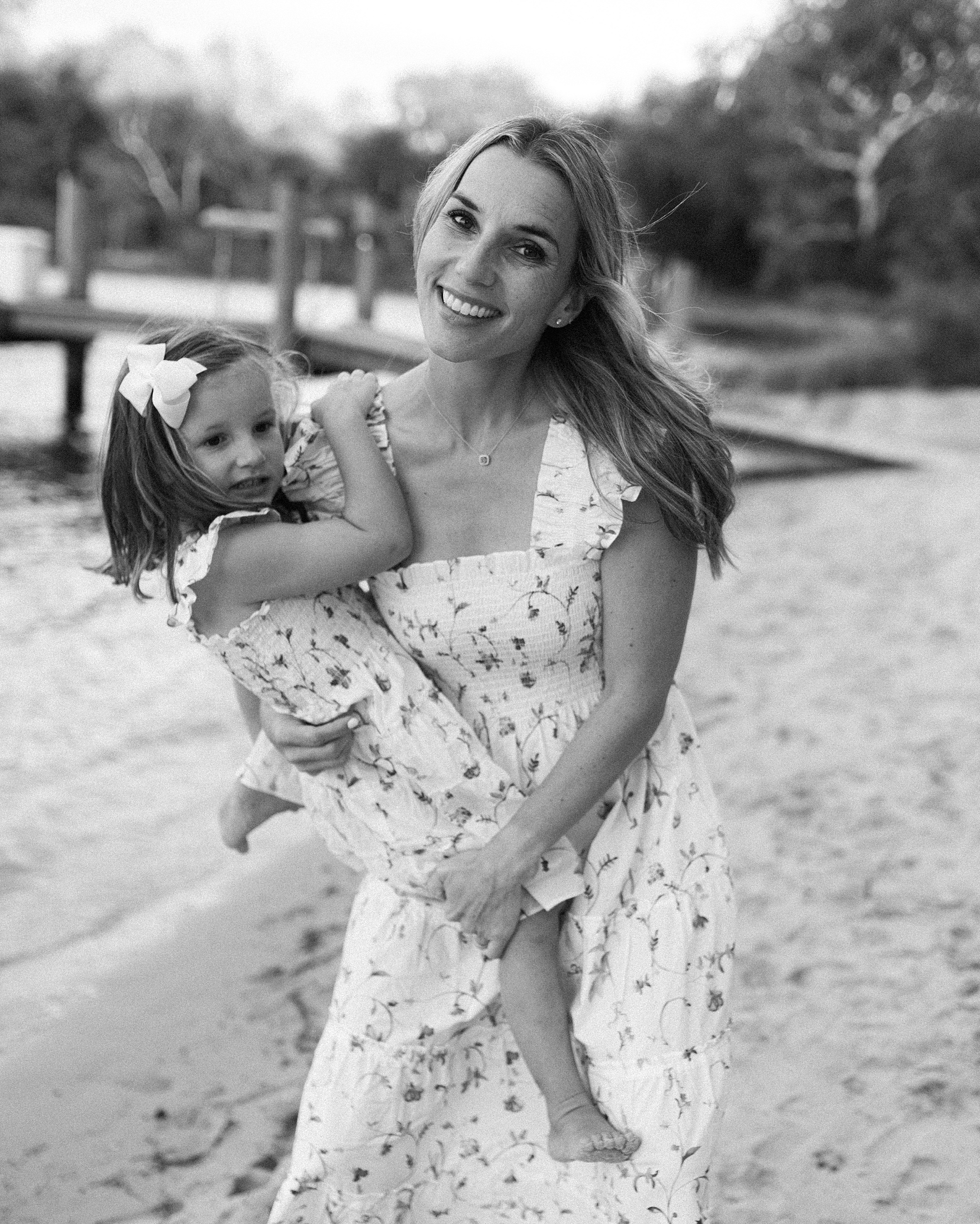 mom holds daughter by the water