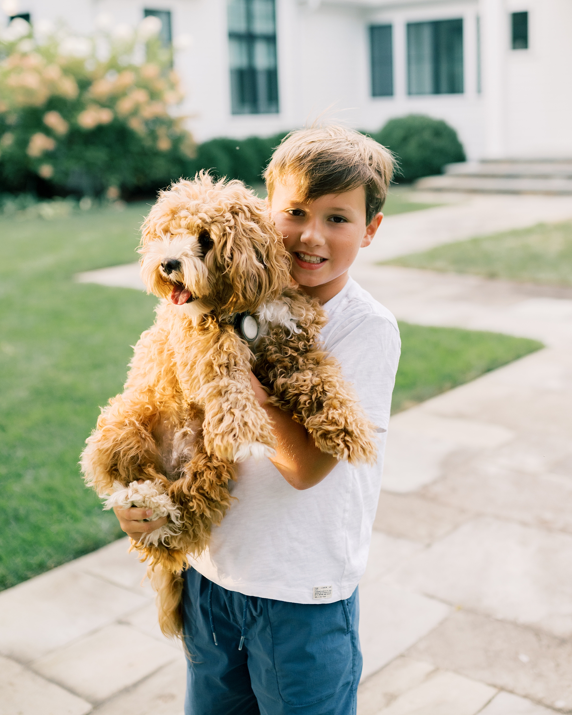 little boy holding family dog 