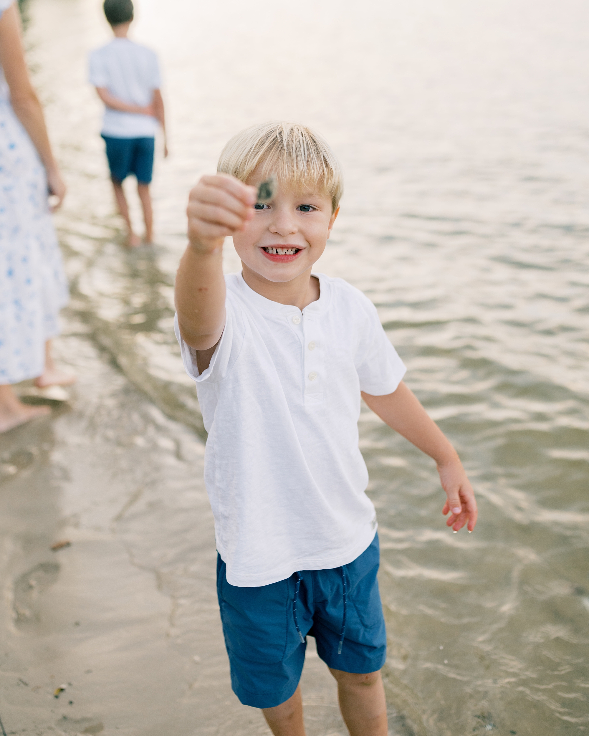 boy holds up crab found on shore at family home