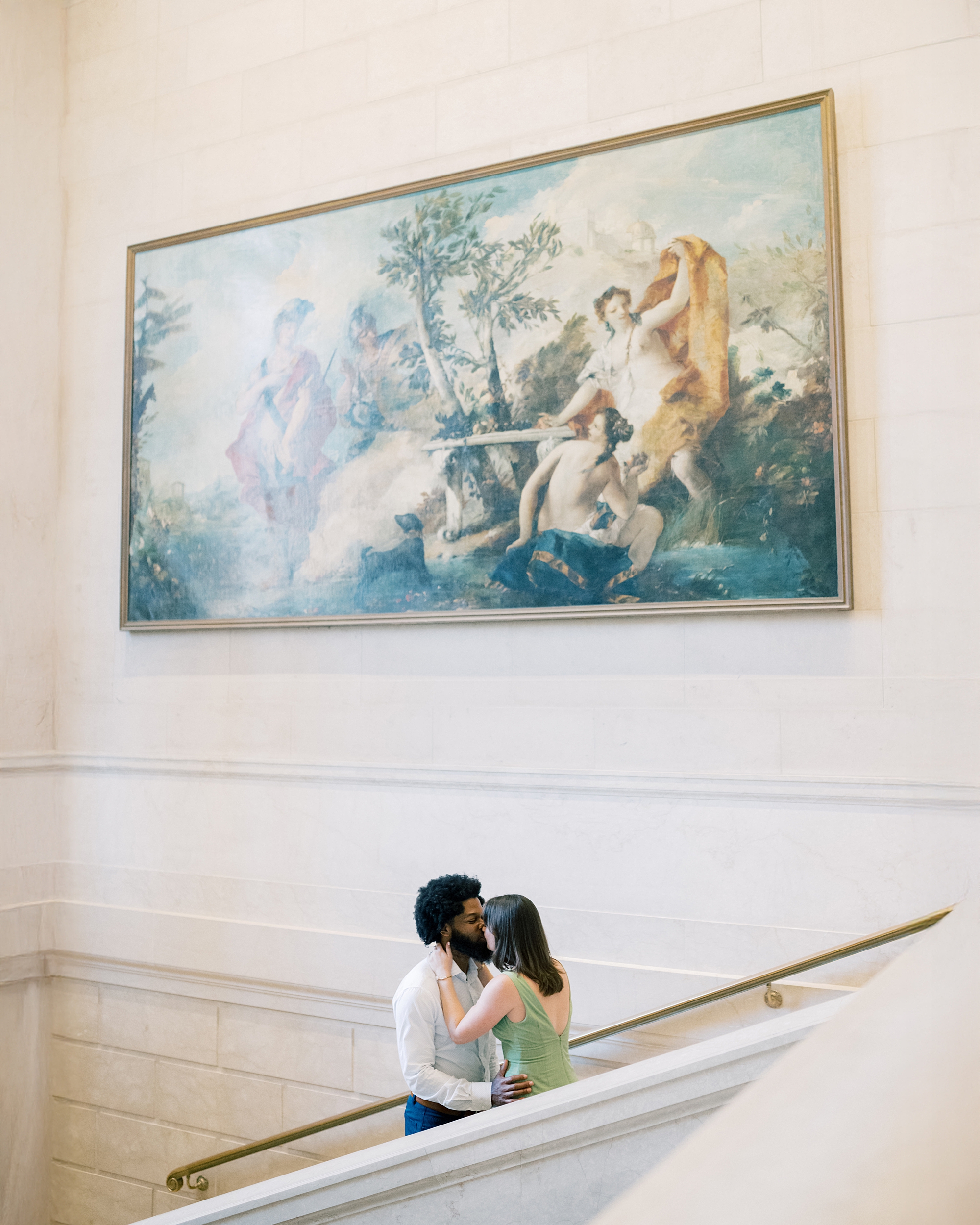 couple on staircase under large painting