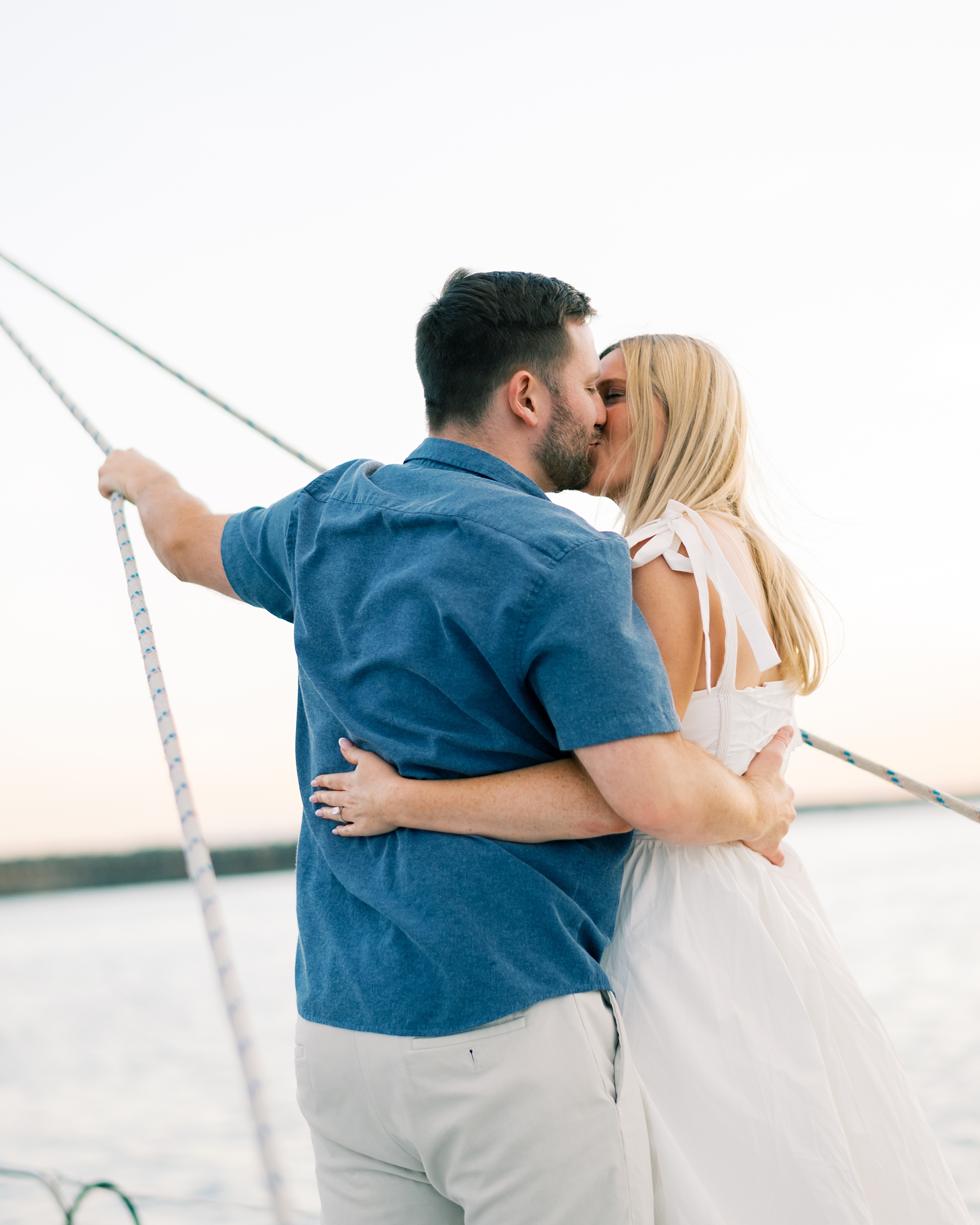couple kiss on a sailboat during their engagement session 