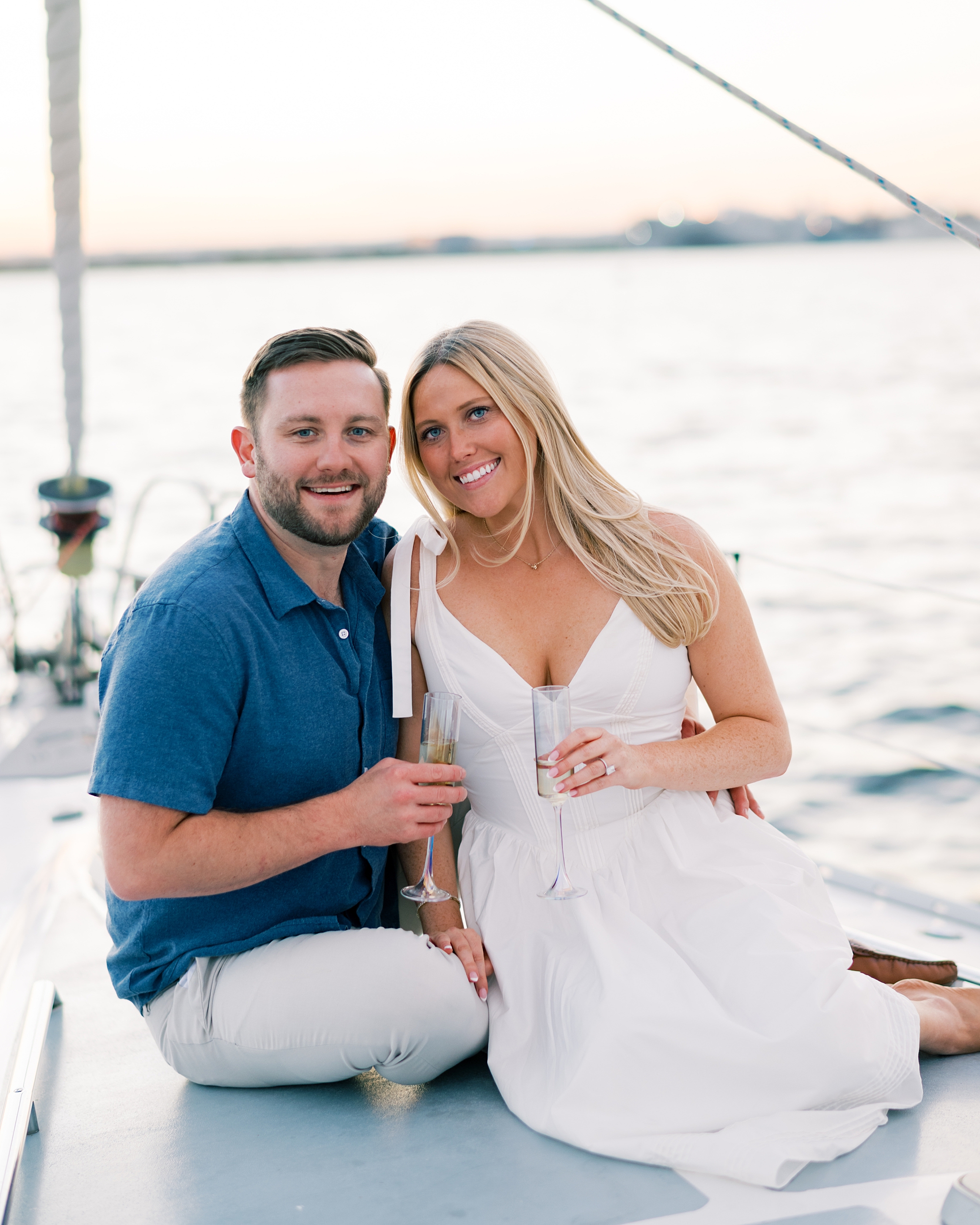 couple share glass of champagne during Sailboat Engagement Session in Baltimore's Inner Harbor