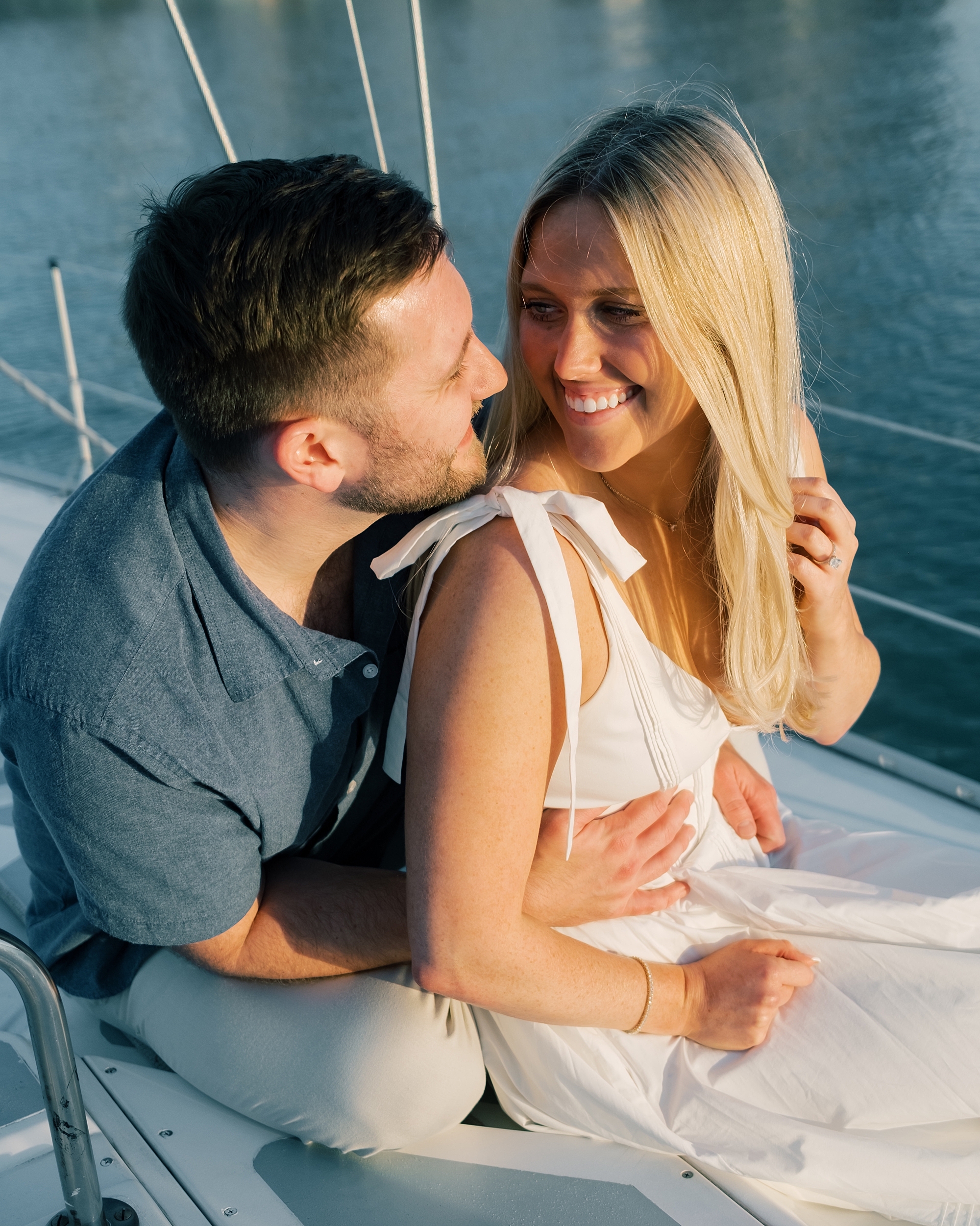 engaged couple sit togehter on sailboat in Baltimore's Inner Harbor