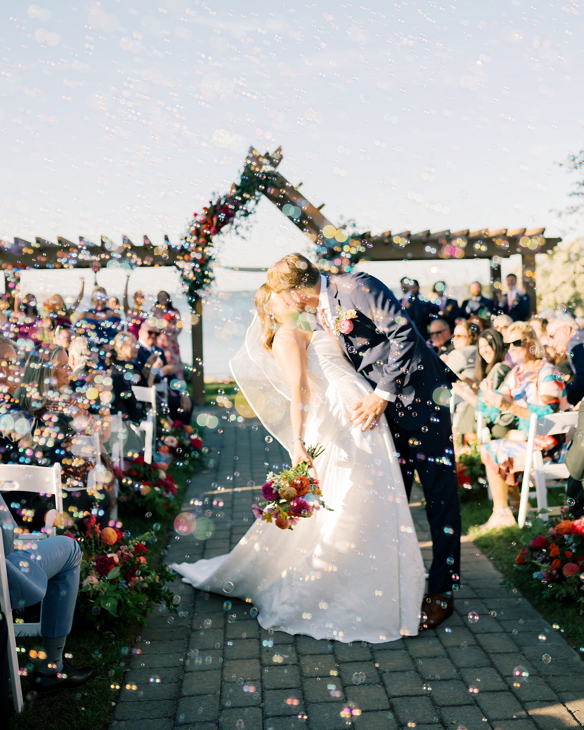 guests blow bubbles as newlyweds exit wedding ceremony 