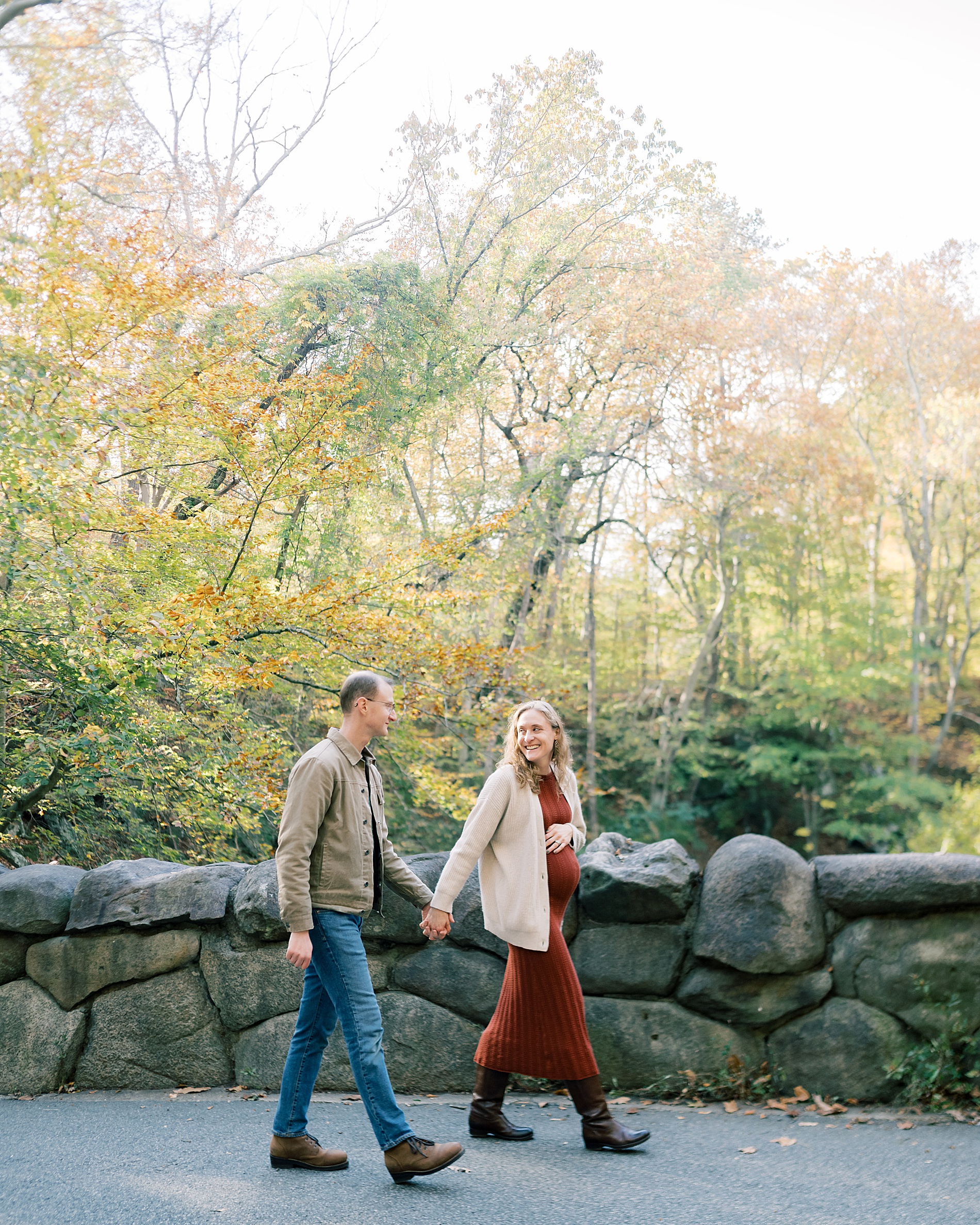 couple hold hands as they walk together through park
