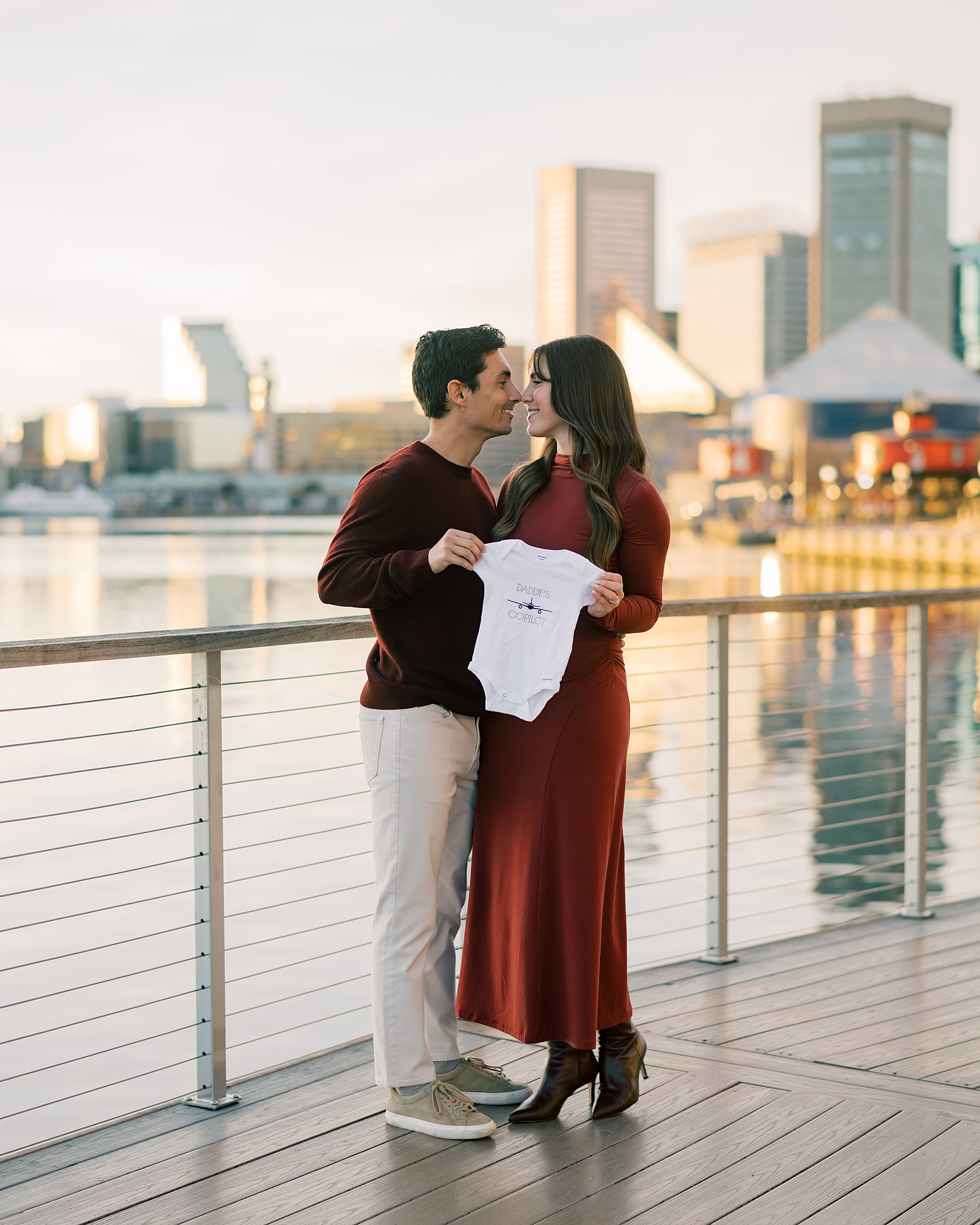 expectant parents hold up onesie 
