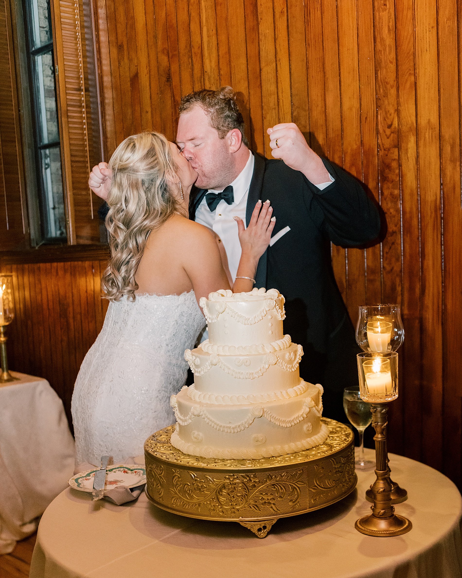 bride and groom kiss during cake cutting 