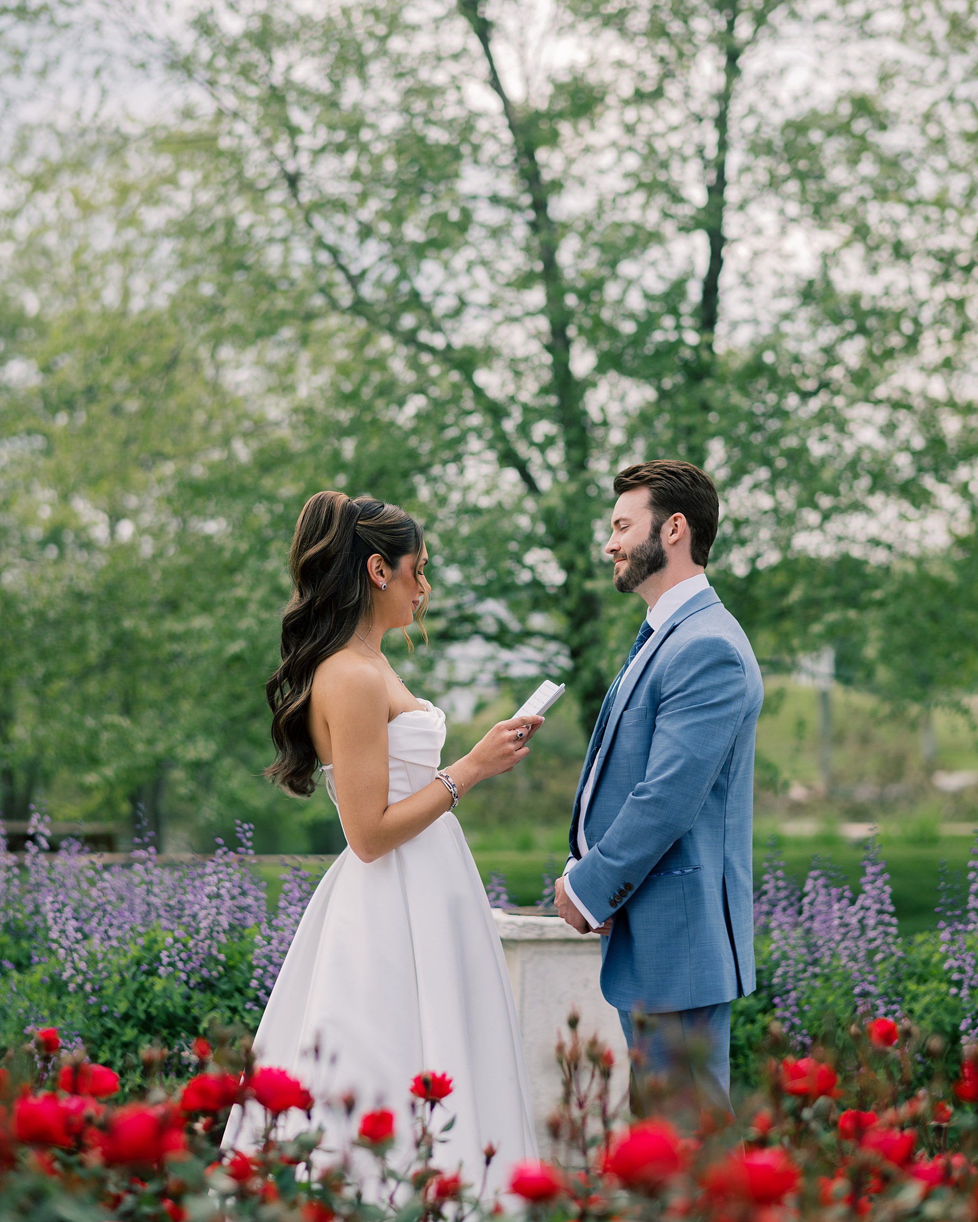 bride reading her vows to groom during private exchange by flowers 