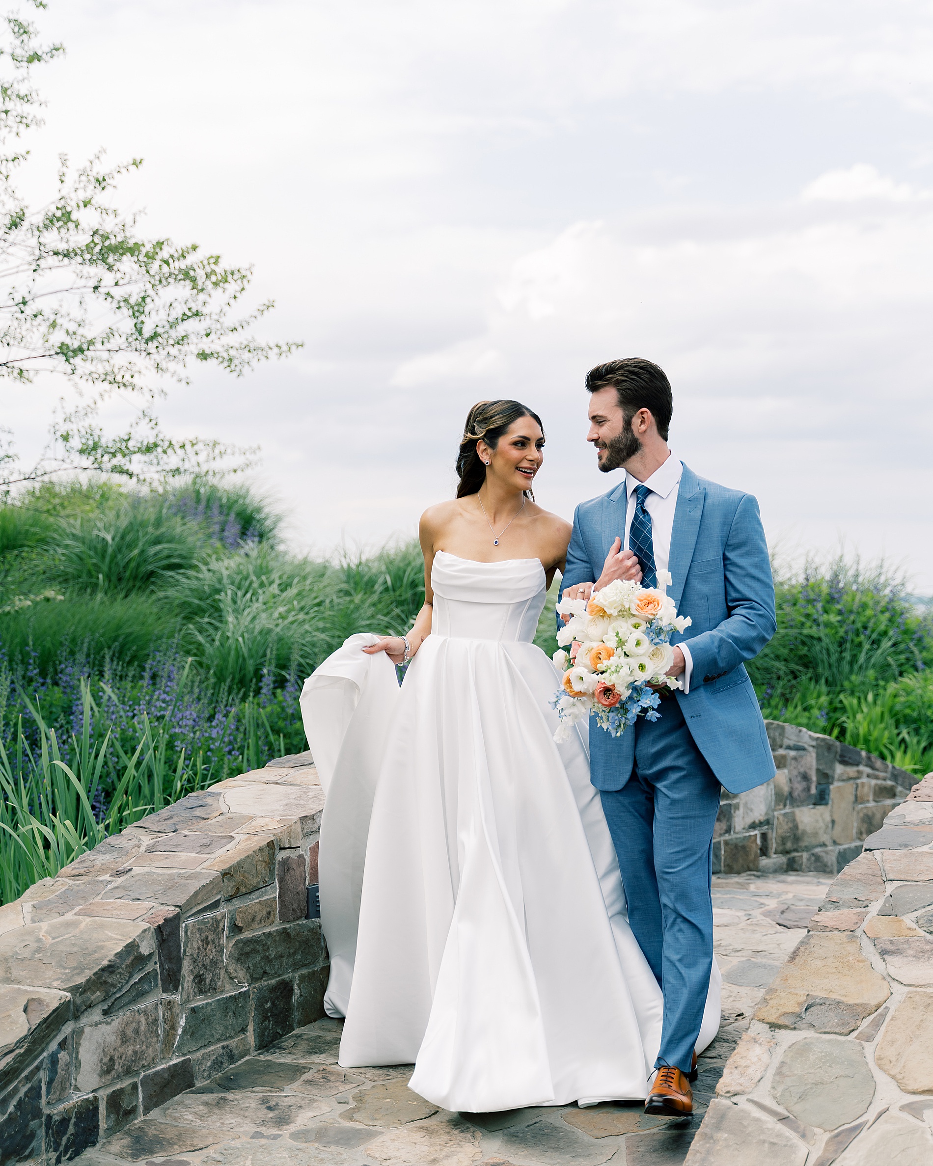 bride and groom walk along stone bridge at Summer Wedding at Herrington on the Bay