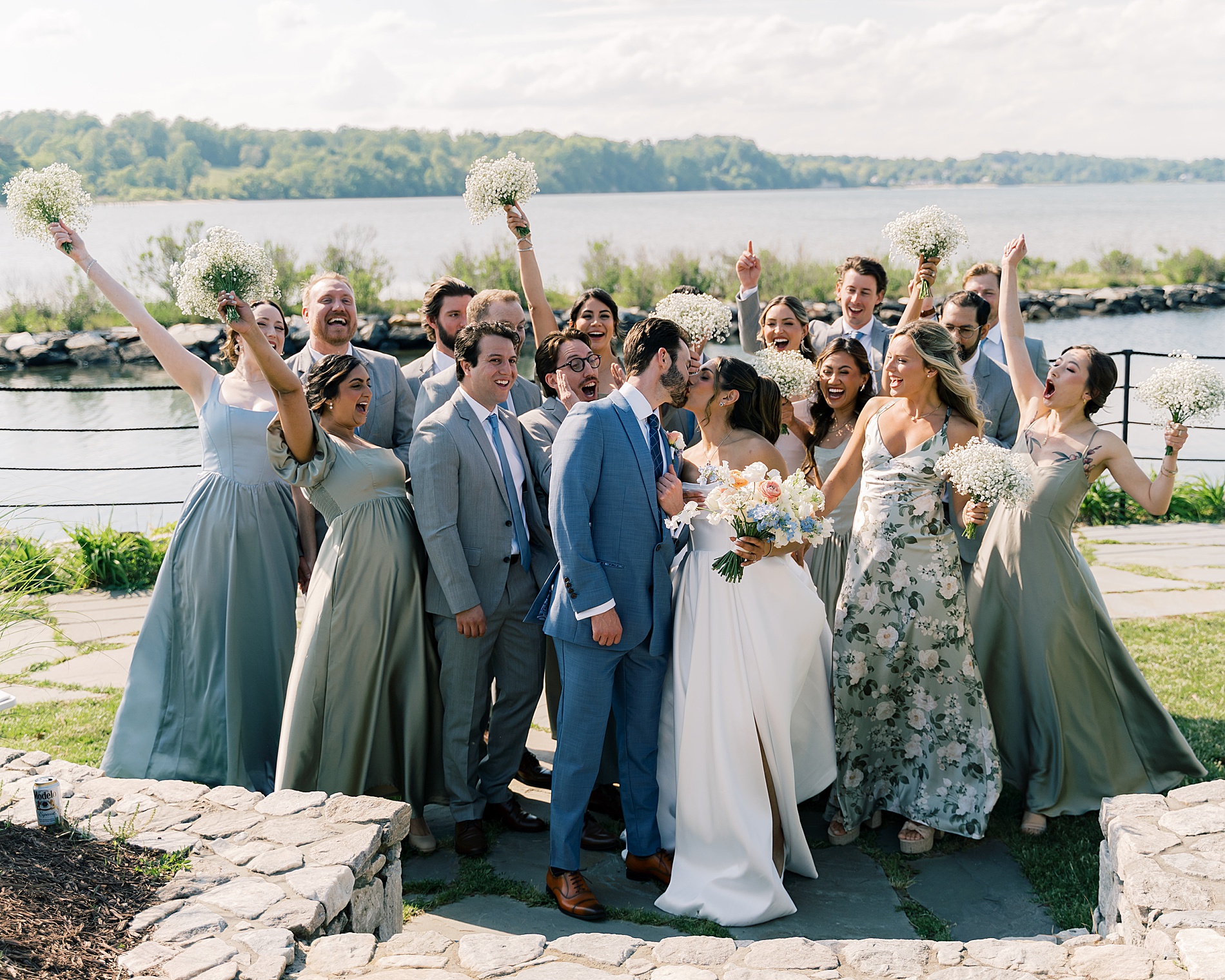 bride and groom kiss as wedding party cheers in the background 