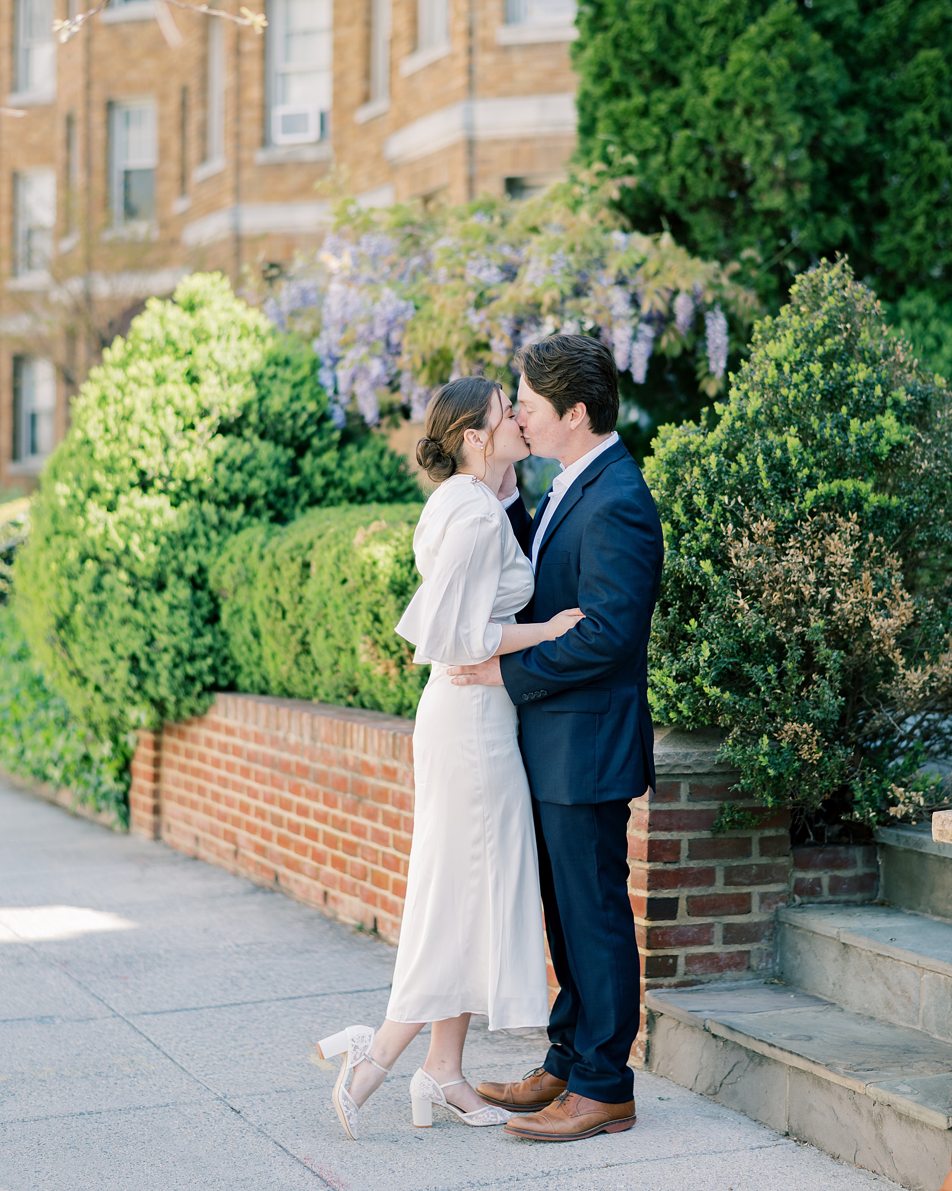 engaged couple kiss on sidewalk 