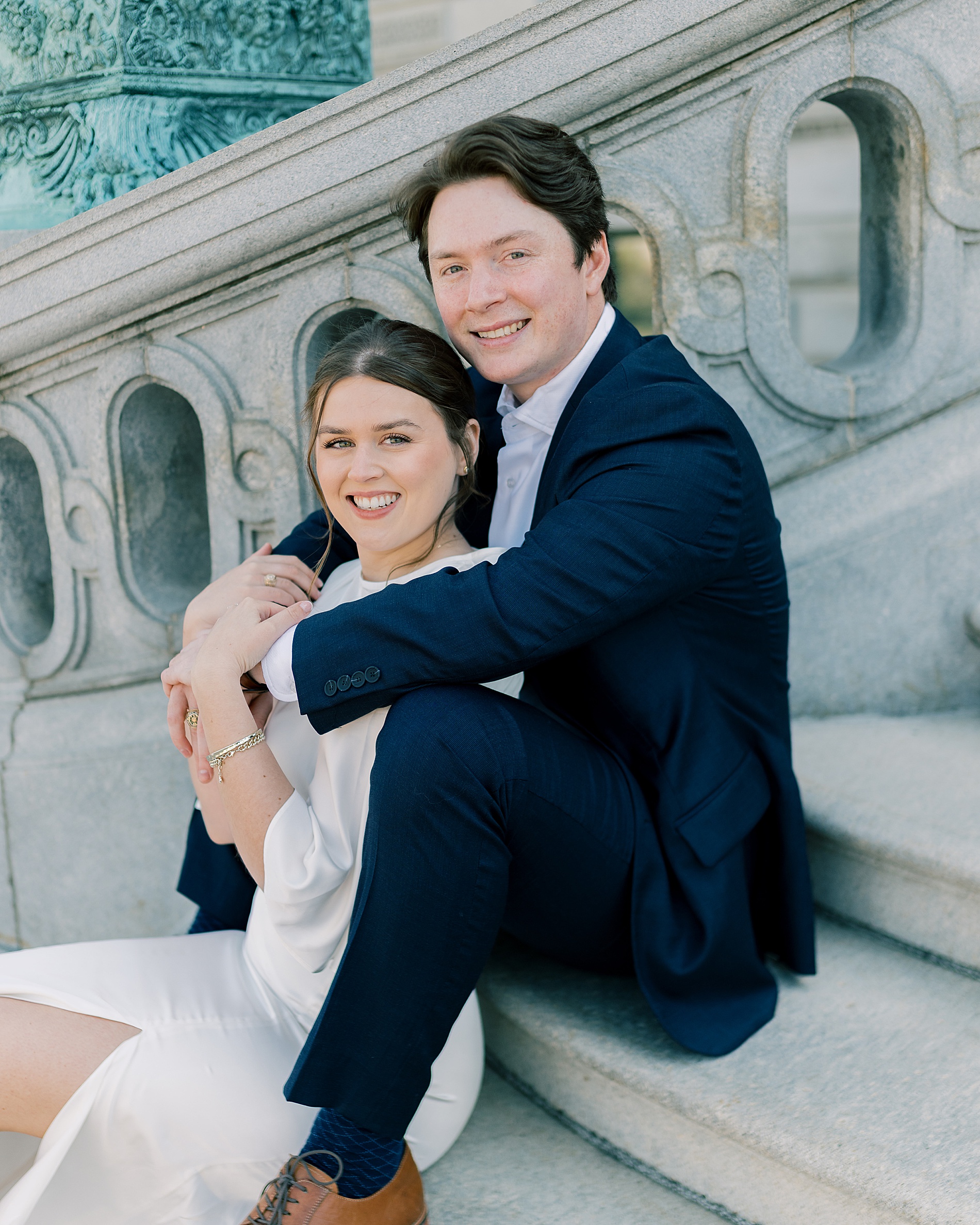 engaged couple sit on stairs of Library in Congress