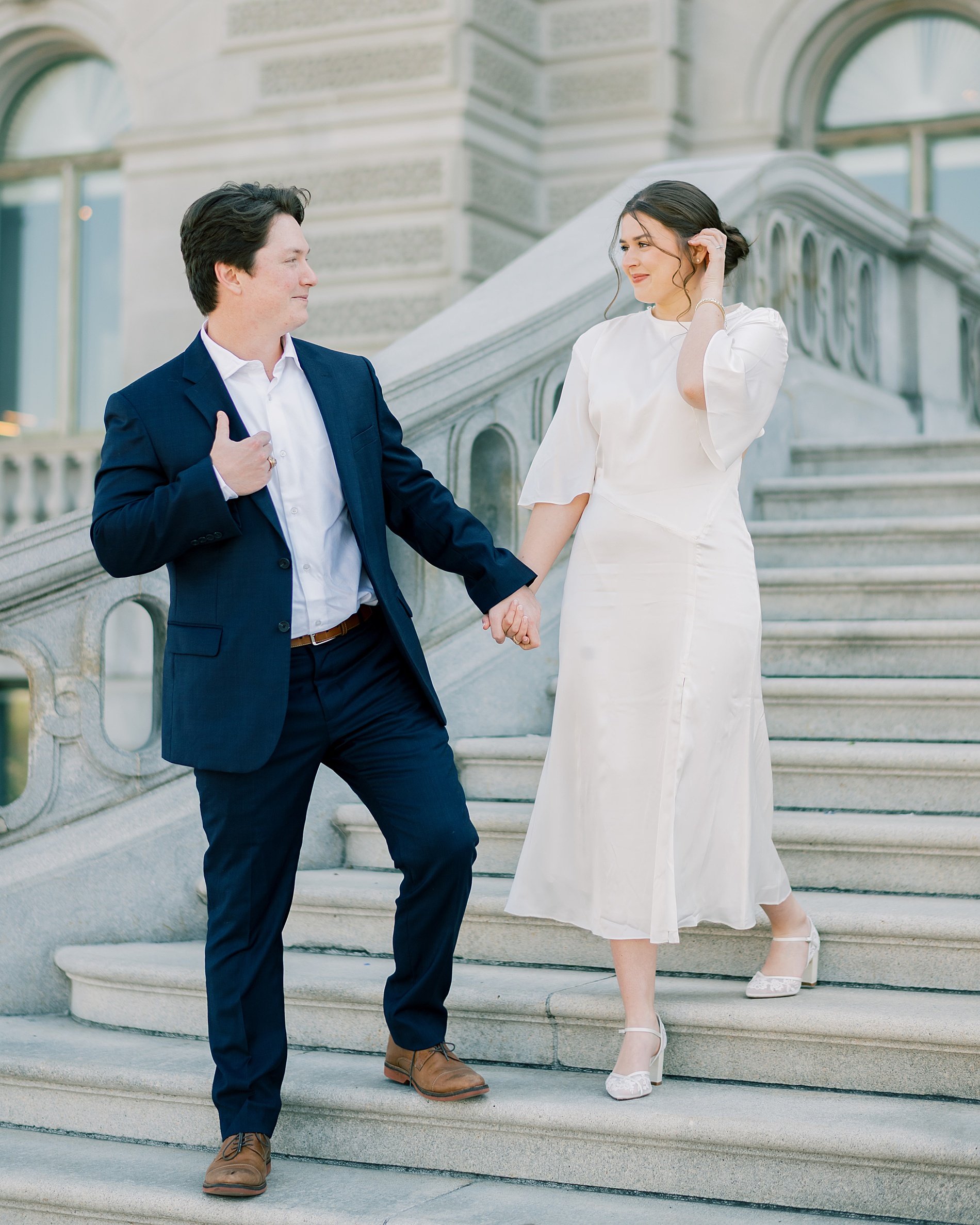 couple hold hands as they walk down staircase together 
