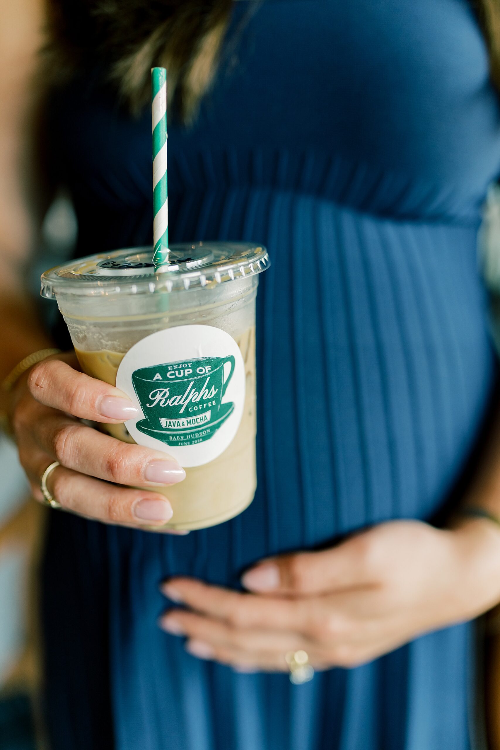 mom places hand on pregnant belly holding a coffee 